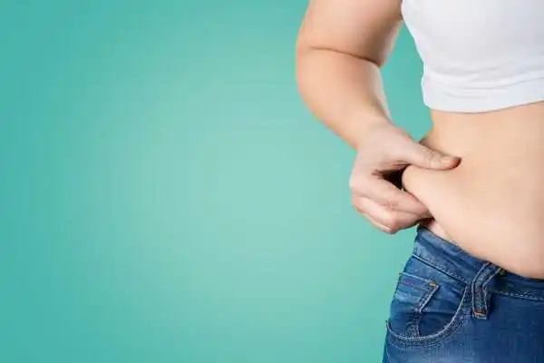 Image of woman pinching her love handles to show weight gain Market Mowbray