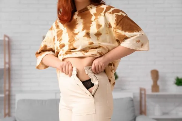 Image of woman trying to do her trousers up after pregnancy weight gain Market Mowbray